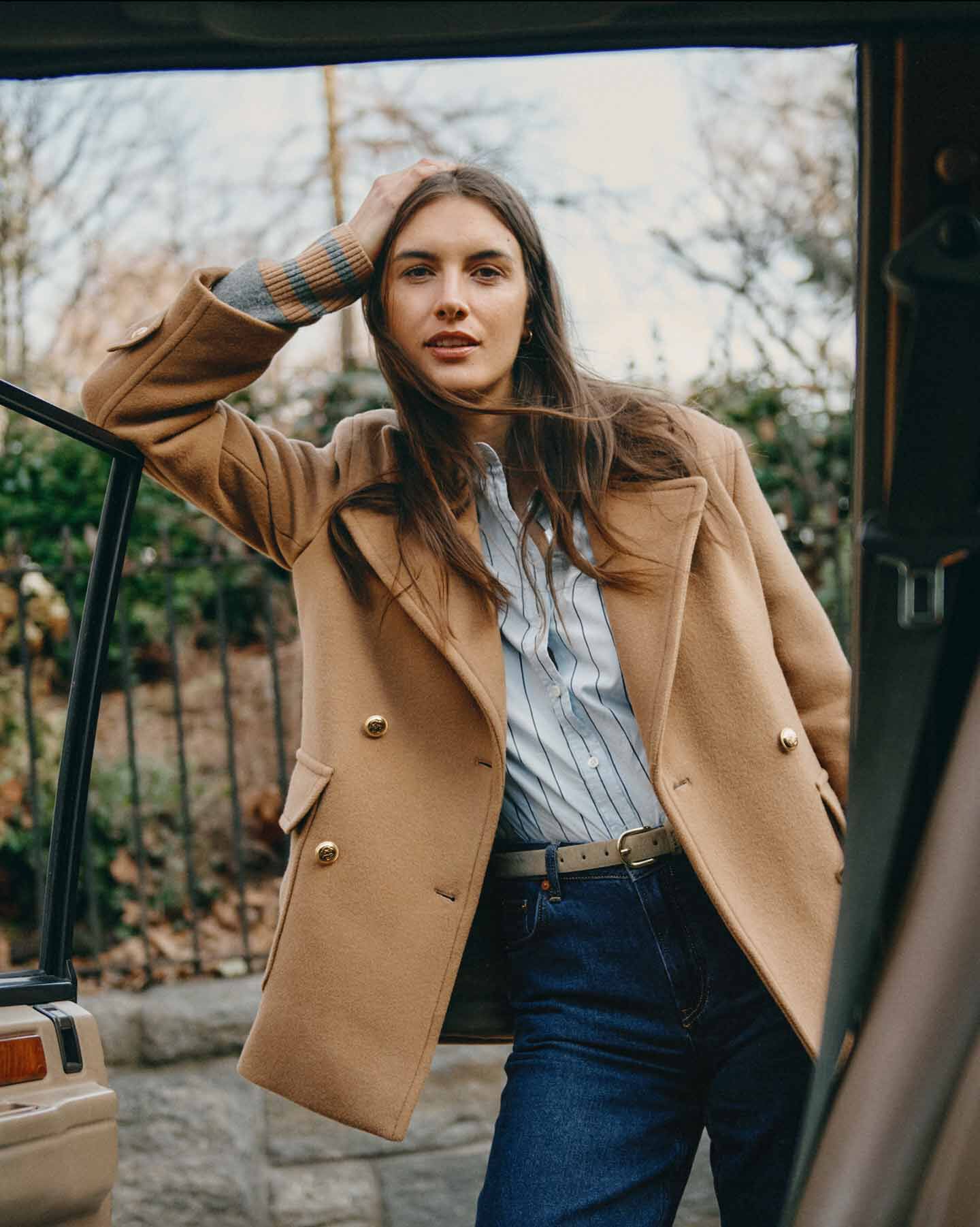 Women in beige peacoat leaning on a car window